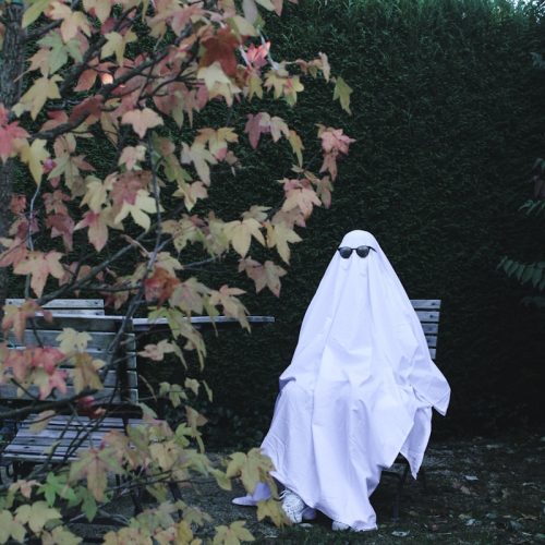 a white ghost sitting on top of a lush green field